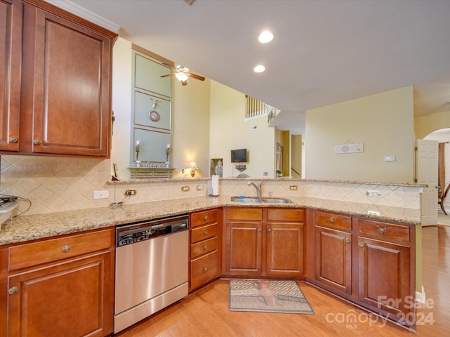 kitchen with sink, light hardwood / wood-style flooring, stainless steel dishwasher, tasteful backsplash, and light stone counters