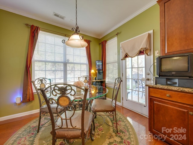 dining area featuring light wood-type flooring and crown molding