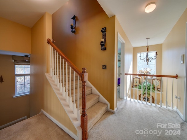 stairs with a chandelier, carpet floors, and plenty of natural light