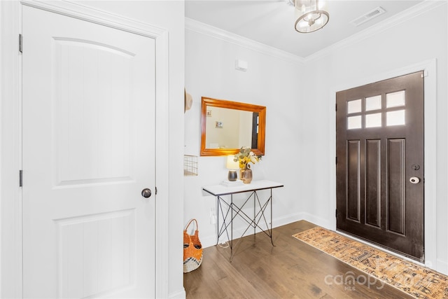 foyer entrance featuring hardwood / wood-style floors, an inviting chandelier, and crown molding