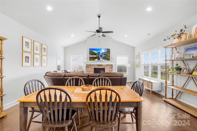 dining area featuring ceiling fan, a stone fireplace, dark hardwood / wood-style flooring, and lofted ceiling