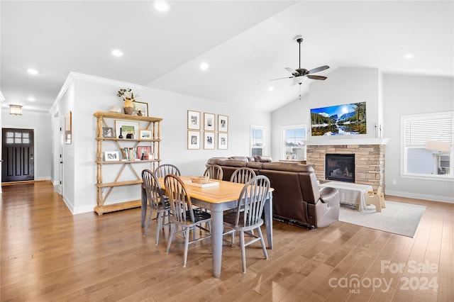 dining area with ceiling fan, crown molding, hardwood / wood-style floors, vaulted ceiling, and a fireplace