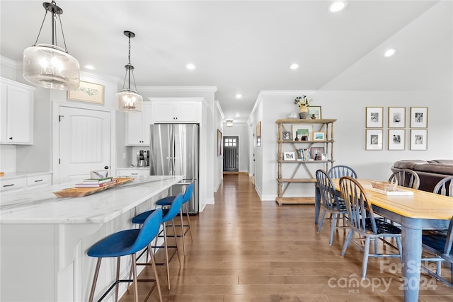 kitchen featuring white cabinets, stainless steel refrigerator, dark wood-type flooring, and light stone counters