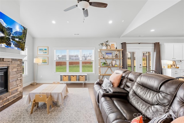 living room with french doors, a fireplace, vaulted ceiling, and light hardwood / wood-style flooring