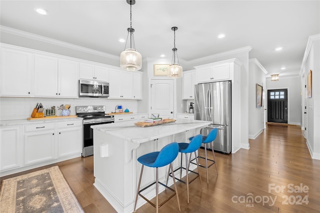 kitchen with a center island, white cabinets, hanging light fixtures, appliances with stainless steel finishes, and dark hardwood / wood-style flooring