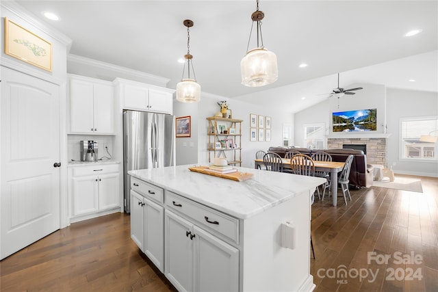 kitchen with a center island, hanging light fixtures, stainless steel fridge, lofted ceiling, and white cabinets