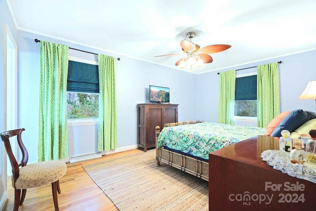 bedroom with ceiling fan, ornamental molding, baseboard heating, and light hardwood / wood-style flooring