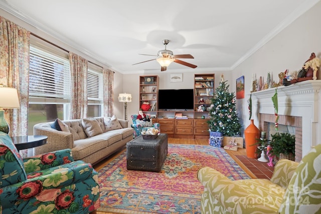 living room with hardwood / wood-style floors, a brick fireplace, ceiling fan, and crown molding