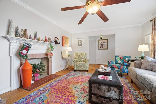 living room with ceiling fan, a fireplace, wood-type flooring, and crown molding