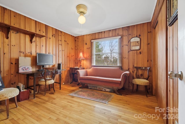 office area with crown molding, wooden walls, ceiling fan, and light wood-type flooring