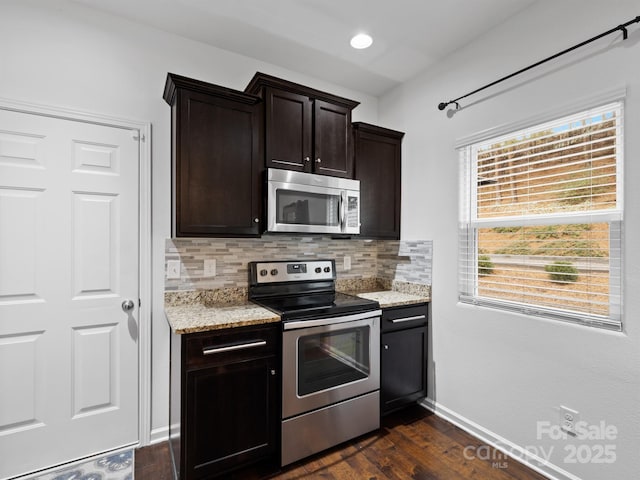 kitchen featuring dark wood-type flooring, tasteful backsplash, dark brown cabinets, stainless steel appliances, and light stone countertops