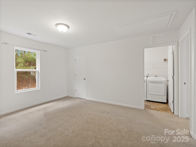 carpeted spare room featuring separate washer and dryer