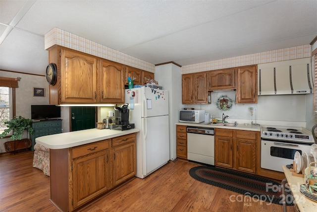 kitchen featuring sink, kitchen peninsula, light hardwood / wood-style floors, white appliances, and ornamental molding