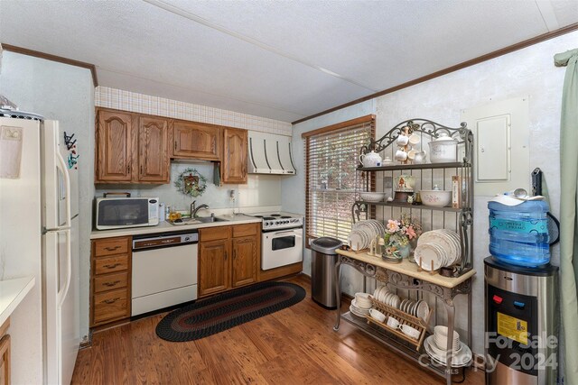 kitchen featuring white appliances, ventilation hood, crown molding, dark wood-type flooring, and sink