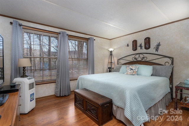 bedroom featuring hardwood / wood-style flooring, crown molding, and multiple windows