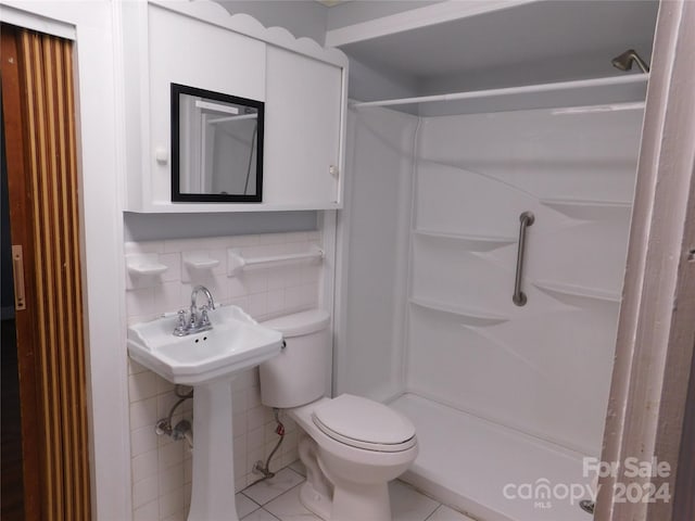 bathroom featuring toilet, a shower, and tile walls