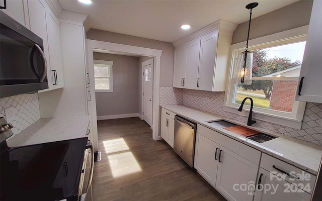 kitchen featuring white cabinetry, sink, dark hardwood / wood-style floors, pendant lighting, and appliances with stainless steel finishes