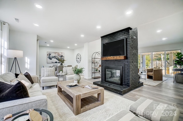 living room featuring light wood-type flooring and a brick fireplace