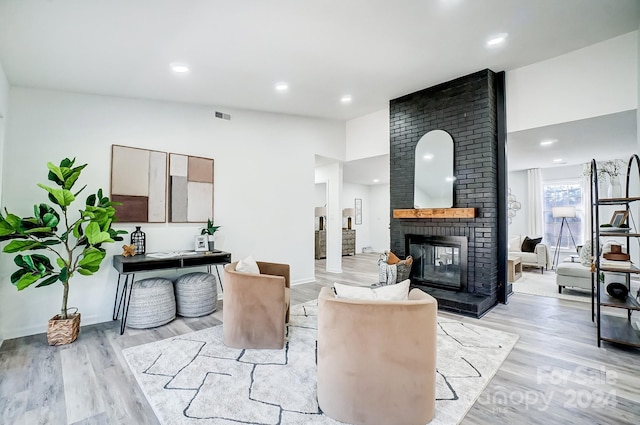 living room featuring light hardwood / wood-style flooring and a brick fireplace