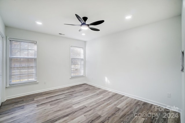 empty room with plenty of natural light, ceiling fan, and light hardwood / wood-style flooring