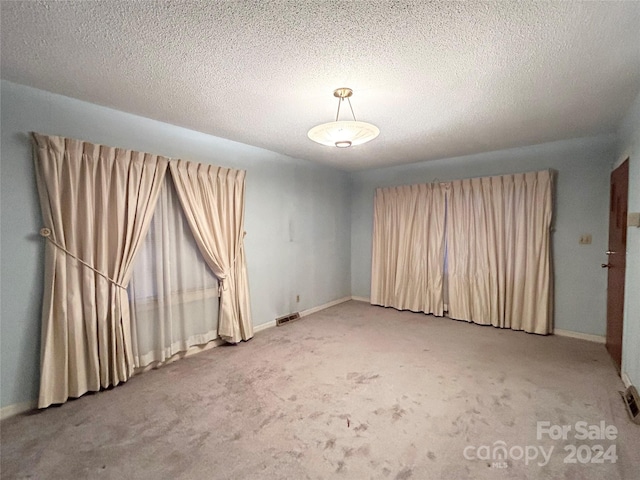 carpeted empty room with a textured ceiling