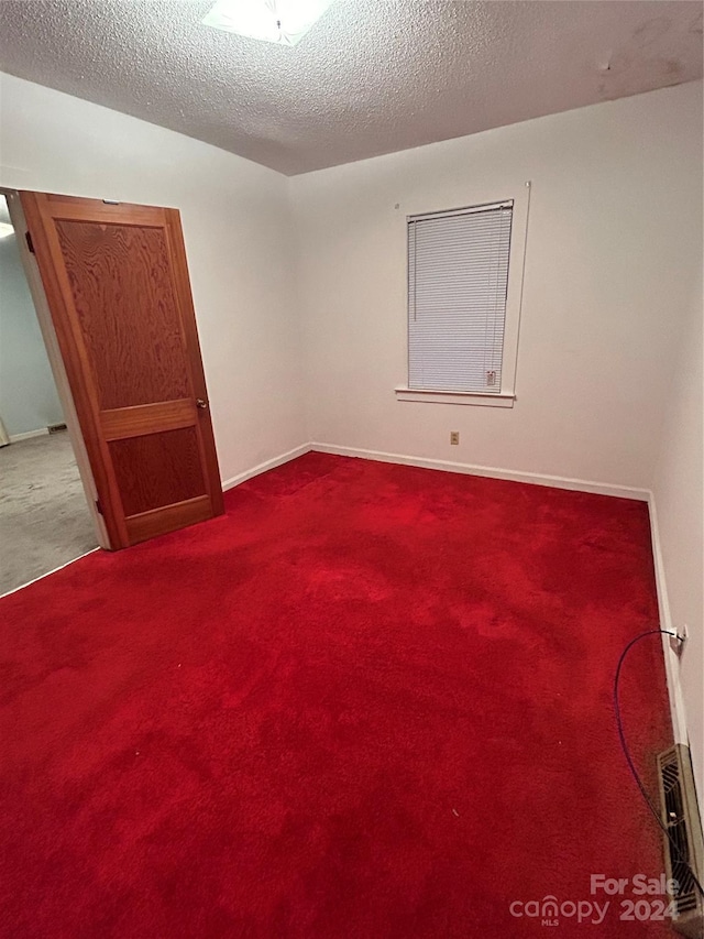 carpeted empty room with a textured ceiling