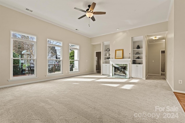 unfurnished living room with light colored carpet, ceiling fan, ornamental molding, and a premium fireplace