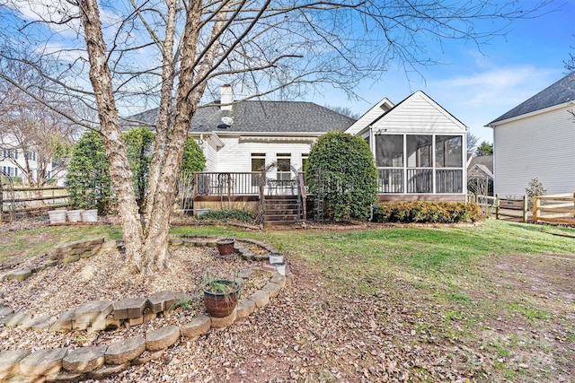 rear view of property with a deck, a lawn, and a sunroom