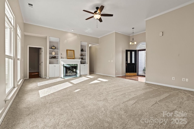 unfurnished living room featuring crown molding, ceiling fan with notable chandelier, carpet floors, and a healthy amount of sunlight