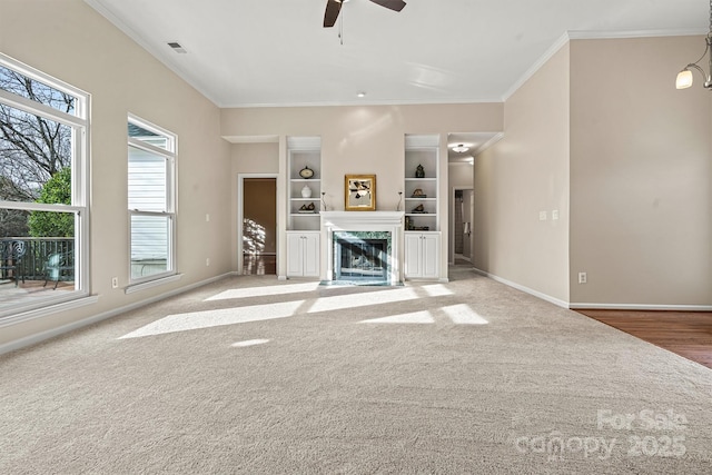 unfurnished living room featuring ceiling fan, ornamental molding, a fireplace, and light carpet