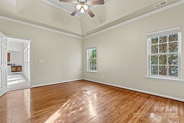 empty room featuring crown molding, a tray ceiling, and light hardwood / wood-style flooring