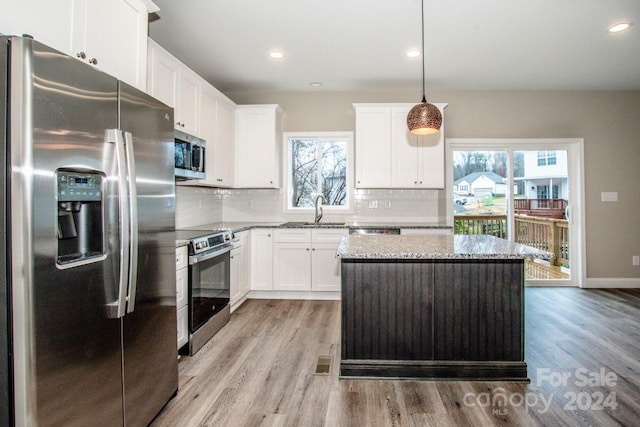 kitchen featuring a healthy amount of sunlight, hanging light fixtures, stainless steel appliances, and light hardwood / wood-style flooring