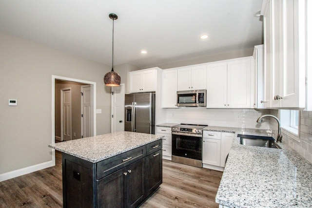 kitchen featuring pendant lighting, a center island, stainless steel appliances, and light hardwood / wood-style floors