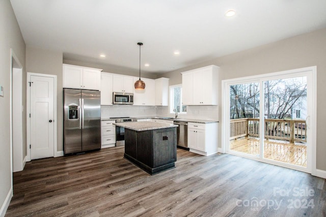 kitchen with stainless steel appliances, dark wood-type flooring, white cabinets, a center island, and hanging light fixtures