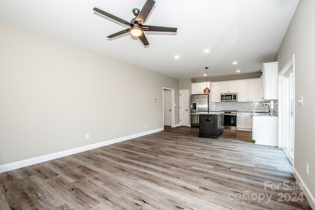 kitchen with white cabinetry, a center island, wood-type flooring, and appliances with stainless steel finishes