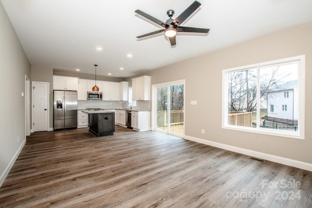 kitchen featuring appliances with stainless steel finishes, decorative light fixtures, a kitchen island, and a wealth of natural light