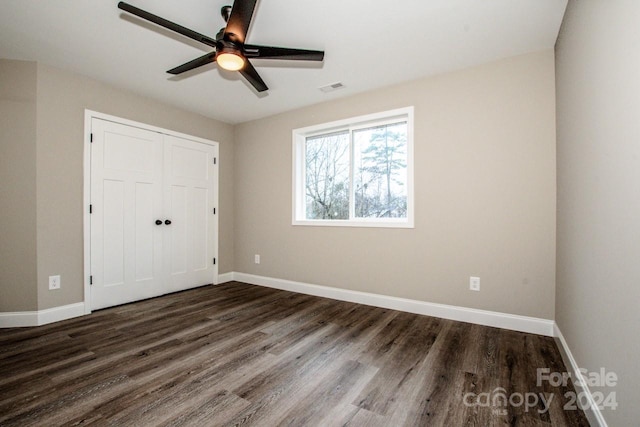 unfurnished bedroom featuring a closet, dark hardwood / wood-style floors, and ceiling fan