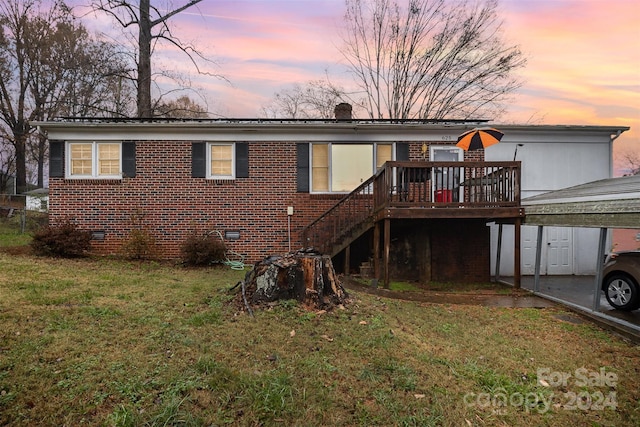 back house at dusk with a lawn and a deck