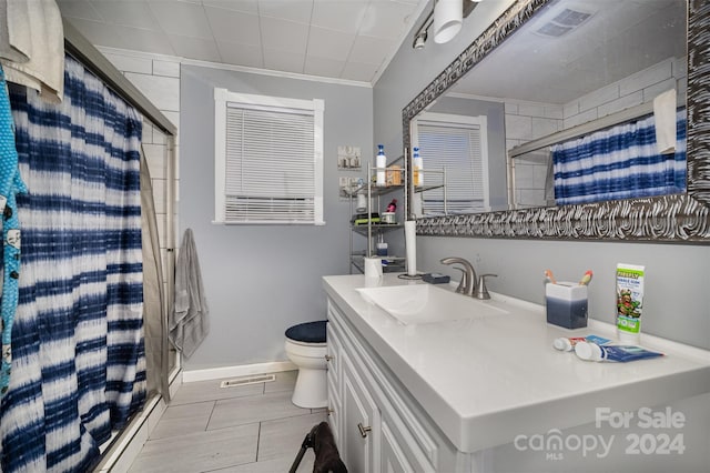 bathroom featuring tiled shower, toilet, vanity, and ornamental molding