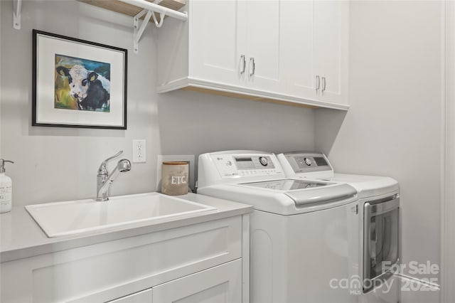 laundry area featuring cabinet space, a sink, and separate washer and dryer