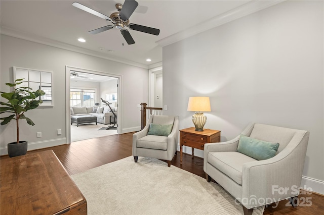 living area featuring baseboards, wood finished floors, and crown molding