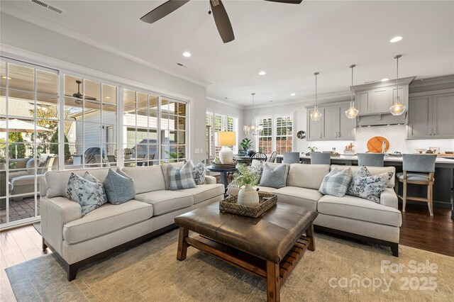 living area featuring light wood-style flooring, visible vents, crown molding, and recessed lighting