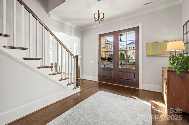 entrance foyer with crown molding, visible vents, wood finished floors, baseboards, and stairs