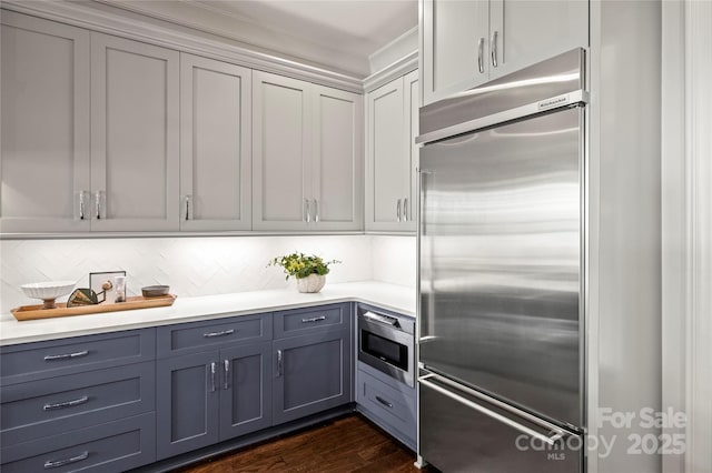 kitchen with gray cabinetry, light countertops, dark wood finished floors, and built in appliances