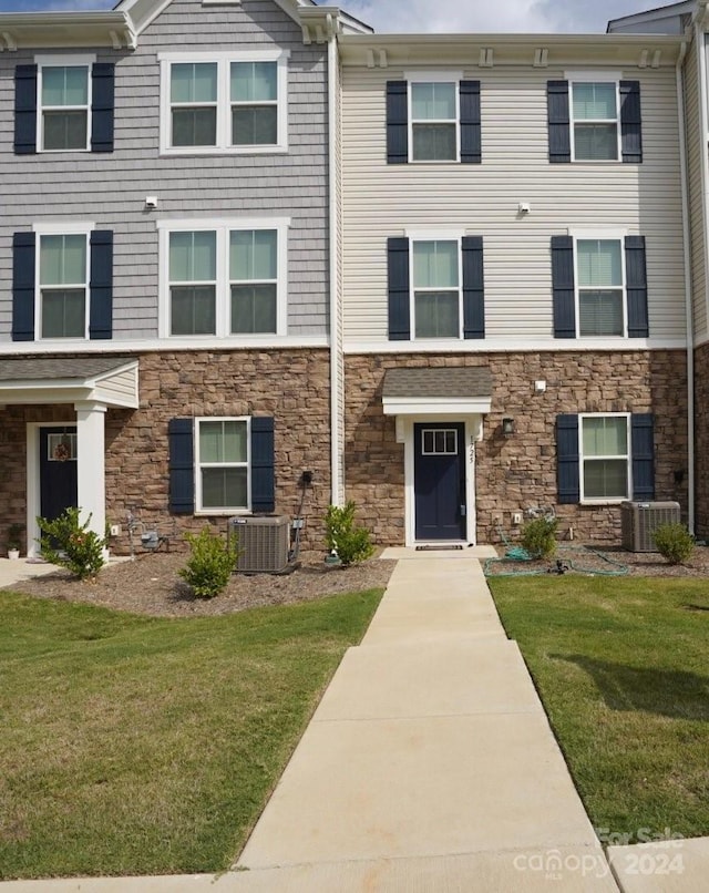 townhome / multi-family property featuring central AC unit and a front yard