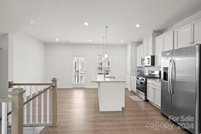 kitchen featuring white cabinetry, stainless steel appliances, hardwood / wood-style floors, an island with sink, and pendant lighting