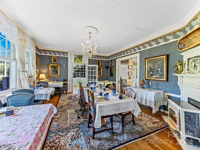 dining area with crown molding, wood-type flooring, a textured ceiling, and a notable chandelier