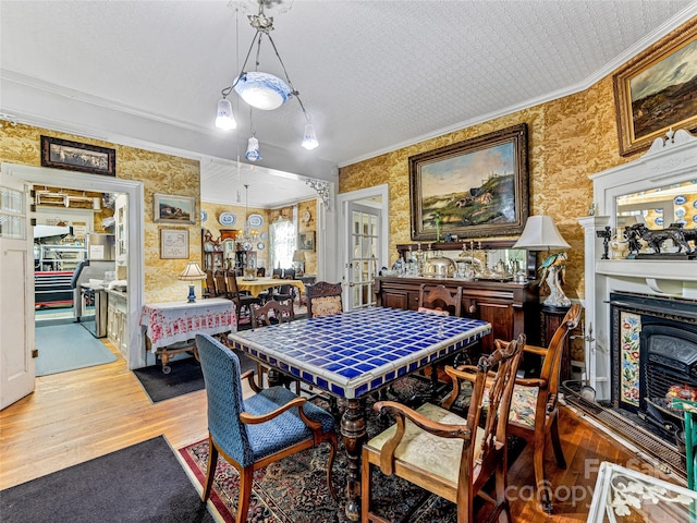 dining room with french doors, a textured ceiling, light hardwood / wood-style floors, and ornamental molding