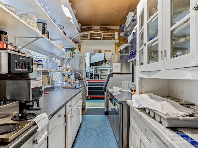 kitchen with wood walls, white cabinetry, and wooden ceiling