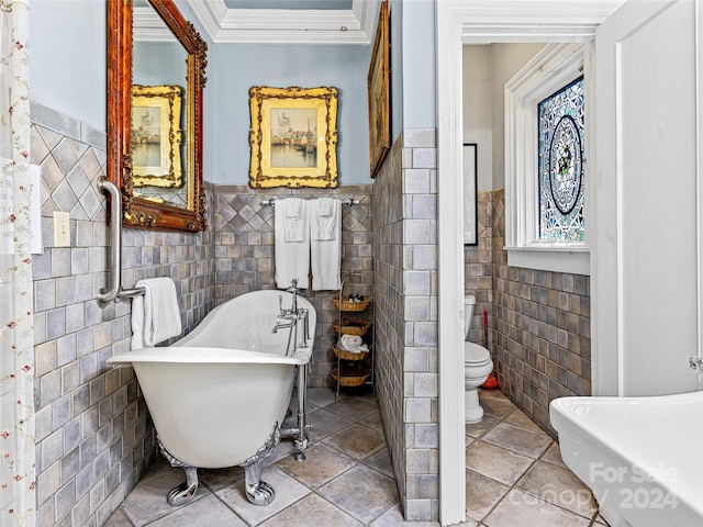 bathroom featuring tile patterned floors, toilet, ornamental molding, tile walls, and a tub